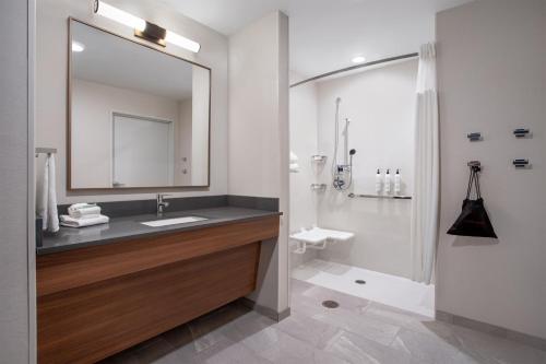 Fairfield by Marriott Inn & Suites Indianapolis Plainfield في بلينفيلد: حمام مع حوض ودش مع مرآة