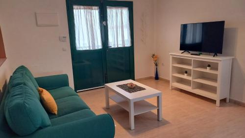 a living room with a green couch and a tv at Sunny in Antigua