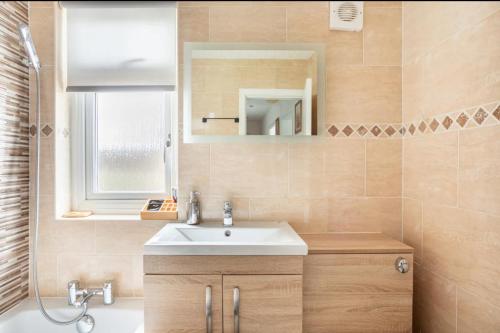 uma casa de banho com um lavatório e um espelho em Captivating 2 bedroom home with jacuzzi and conservatory em Hamilton