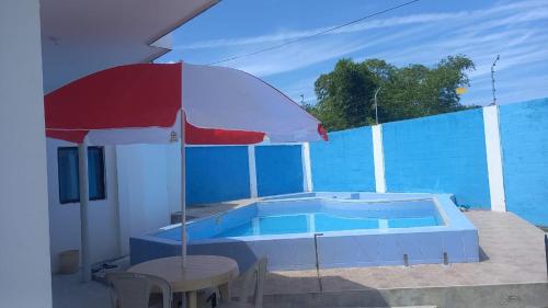 a pool with a red umbrella and a table at Casa Tonsupa in Tonsupa