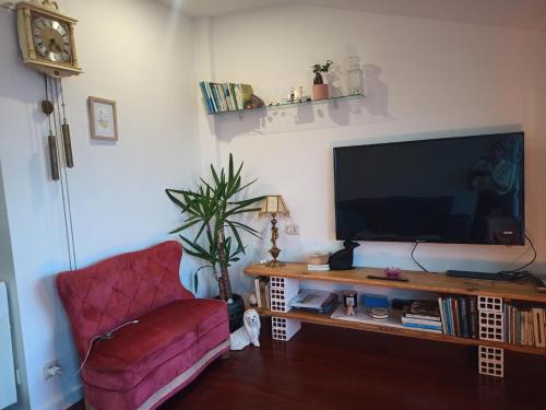 a living room with a television and a red chair at Ático acogedor en casco antiguo in Cangas de Morrazo