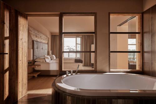 a bathroom with a tub and a bedroom with a bed at COMO Alpina Dolomites in Alpe di Siusi