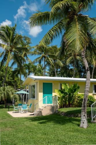 a yellow house with a blue door and palm trees at Bay Harbor Lodge in Key Largo