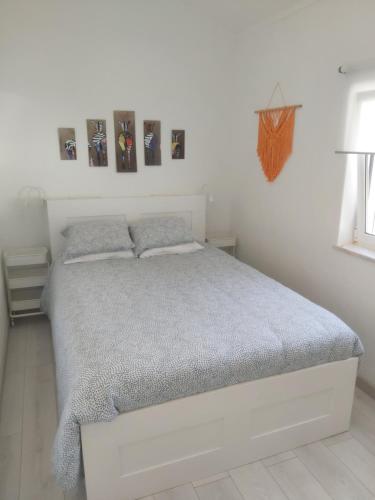 House of Love Portimão في بورتيماو: سرير أبيض في غرفة نوم بيضاء مع صور على الحائط