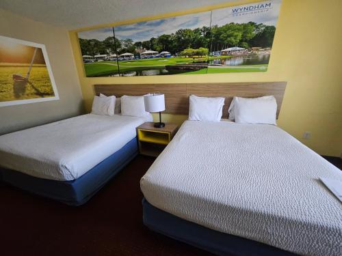 a hotel room with two beds and a painting on the wall at Days Inn by Wyndham Greensboro NC in Greensboro