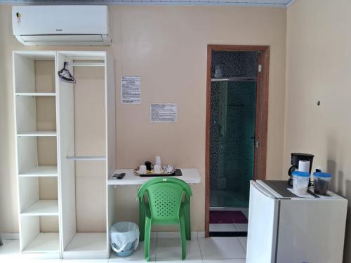una pequeña cocina con una silla verde en una habitación en Edward Suíte Manaus 03 en Manaus