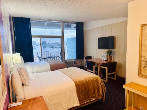 a hotel room with two beds and a desk and a window at Foghorn Harbor Inn in Los Angeles