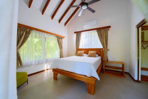 a bedroom with a white bed and two windows at Casa Kristel - Exquisite Villa Getaway in Puerto Viejo