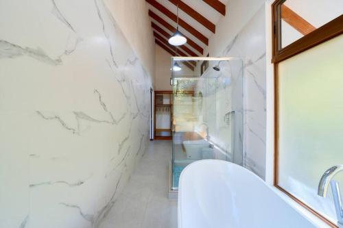 a bathroom with a shower and a white marble wall at Casa Kristel - Exquisite Villa Getaway in Puerto Viejo