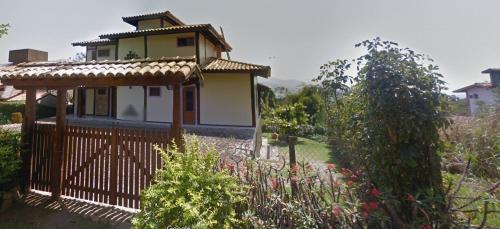 a small house with a fence in a garden at casa ilha bela in Ilhabela