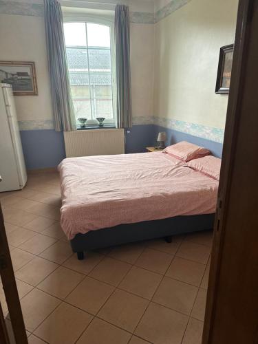 - une chambre avec un lit avec des draps roses et une fenêtre dans l'établissement ferme d'herlaimont 1, à Chapelle-lez-Herlaimont