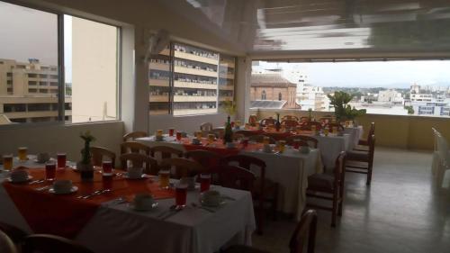una sala da pranzo con tavoli, sedie e finestre di Hotel Sulicam a Neiva