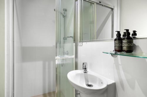 ein weißes Bad mit einem Waschbecken und einer Dusche in der Unterkunft Bayona Apartment 2, Little Cove in Noosa Heads