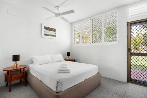 a white bedroom with a bed and a window at Bayona Apartment 2, Little Cove in Noosa Heads