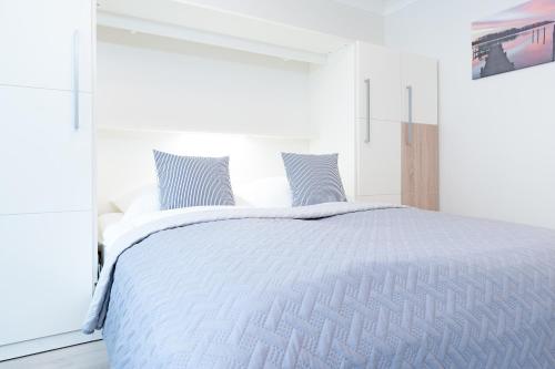 a white bedroom with a white bed with blue pillows at Haus Schwanensee Studio 15 in Bosau