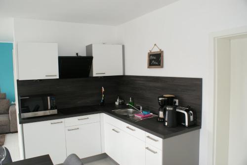 a kitchen with white cabinets and a black counter top at Strandhaus Rose in Juist