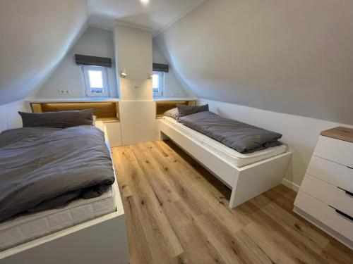 a bedroom with two beds and wooden floors at Dünen Lodge 6 in Juist
