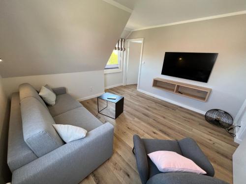 ein Wohnzimmer mit einem Sofa und einem Flachbild-TV in der Unterkunft Dünen Lodge 6 in Juist
