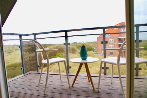 2 Stühle und ein Tisch auf dem Balkon in der Unterkunft Strandhaus Rose in Juist