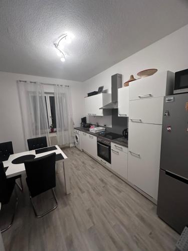 eine Küche mit weißen Geräten sowie einem Tisch und Stühlen in der Unterkunft Wohnen am Wasser - Privatzimmer - Sharing Apartment in Konstanz