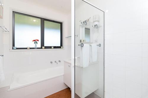 a white bathroom with a shower and a window at Ocean Spray Retreat in Port Fairy