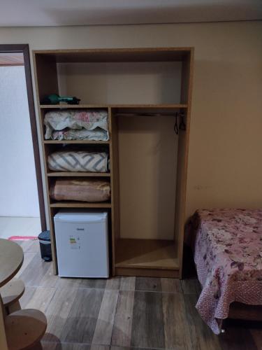 una camera con armadio, letto e frigorifero di Pousada Regina a Cambará
