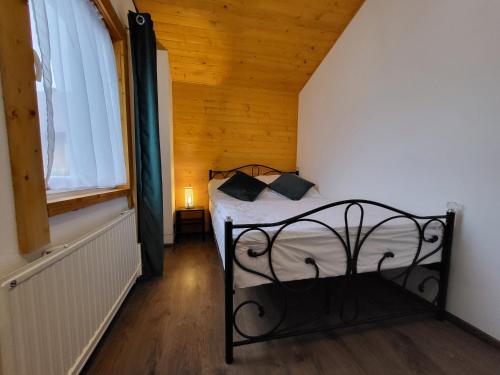 Stroński Domek في سترونيش لونسكي: غرفة نوم بسرير اسود بسقف خشبي