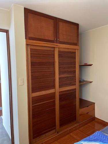 einen Schrank mit Holztüren in einem Schlafzimmer in der Unterkunft Habitación amoblada dentro de departamento amoblado tipo roommate in Lima