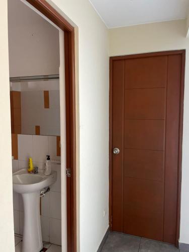 ein Badezimmer mit einem Waschbecken und einer Holztür in der Unterkunft Habitación amoblada dentro de departamento amoblado tipo roommate in Lima