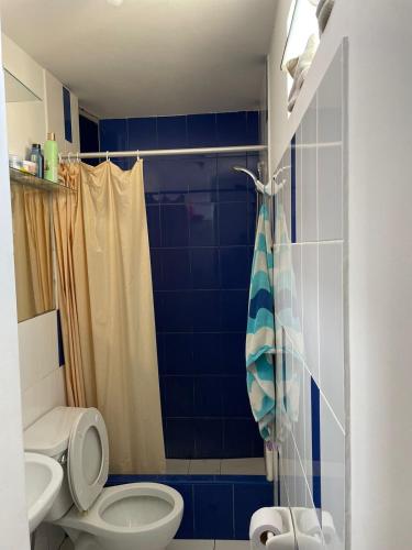 y baño de azulejos azules con aseo y ducha. en Habitación amoblada dentro de departamento amoblado tipo roommate, en Lima