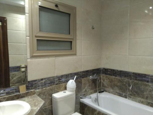 een badkamer met een toilet, een wastafel en een raam bij 5th Settlement Shaya in Caïro