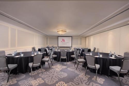 a conference room with tables and chairs and a screen at Lisbon Marriott Hotel in Lisbon