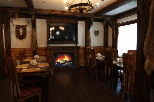 a dining room with a fireplace and tables and a tv at Forest House in Tatariv