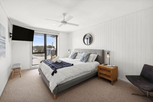 um quarto com uma cama, uma televisão e uma cadeira em Apartment 12 Pacific Apartments em Lorne