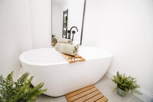 a white bath tub in a bathroom with plants at Brand New Stylish Three Story House! in Thorpe Saint Andrew