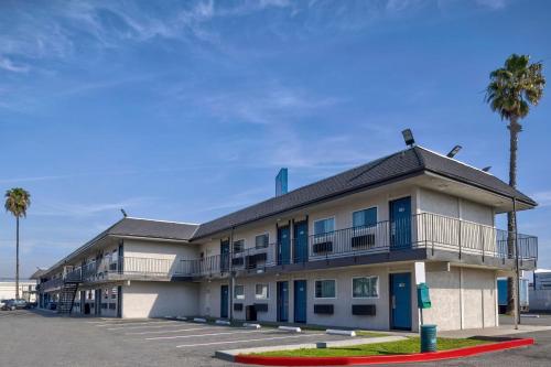 a building with palm trees in front of a parking lot at Motel 6-Anaheim, CA - Fullerton East in Anaheim