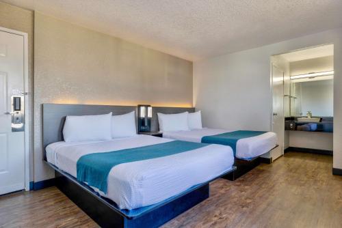 a hotel room with two beds and a mirror at Motel 6-Anaheim, CA - Fullerton East in Anaheim