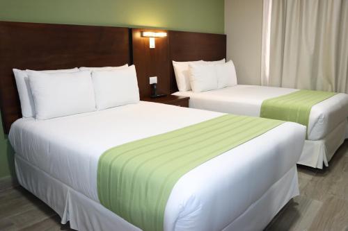 two beds in a hotel room with white and green sheets at Hotel San Agustin Plaza in Latacunga
