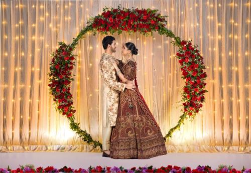 a bride and groom standing under an arch of flowers at Radisson Blu Resort Visakhapatnam in Visakhapatnam