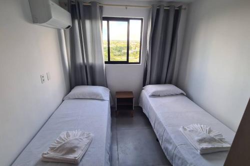 2 Betten in einem kleinen Zimmer mit Fenster in der Unterkunft Aconchego em Carapibus 2-Cobertura Nascente Sul in Conde