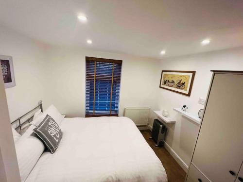 1 dormitorio con cama blanca y ventana en Little Knapp Cottage, East of Church Road, Chichester, West Sussex PO19 7YH, en Chichester