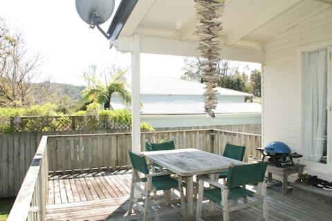 eine Terrasse mit einem Tisch, Stühlen und einem Grill in der Unterkunft Quiet, Private and Central in Tairua