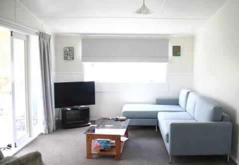 ein Wohnzimmer mit einem blauen Sofa und einem TV in der Unterkunft Quiet, Private and Central in Tairua