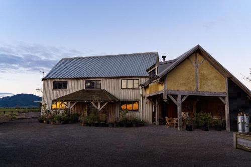 a large wooden barn with a building at housewithnonails in Matamata