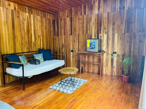 Habitación de madera con sofá y mesa. en Cacahua Paradise Lodge, Río Celeste, en Rio Celeste
