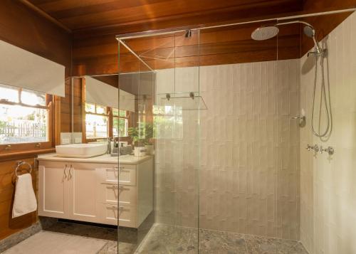 a bathroom with a glass shower with a sink at Maleny Hotel in Maleny