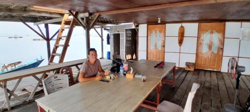 a person sitting at a table on a boat at Ekas beach floating Room and suite in Ekas
