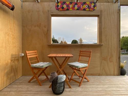 a patio with two chairs and a table and a window at Haven On Tau in Ohakune