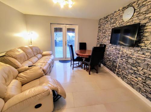 a living room with a couch and a tv on a stone wall at High Rigg House Bradford - Luxury Accomodation with Private Parking in Idle