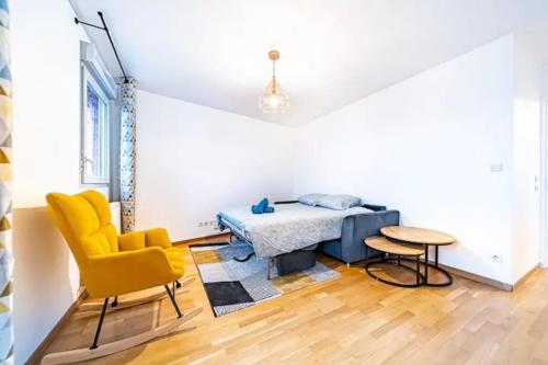 - une chambre avec un lit et une chaise jaune dans l'établissement Joli T2 avec garage gratuit et balcon, à Villeurbanne